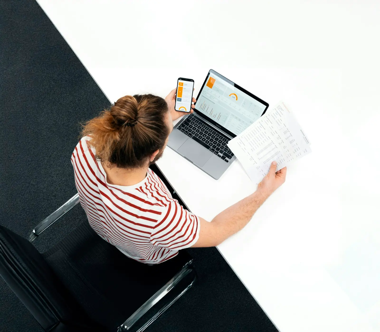 Personne consultant des documents et un ordinateur portable sur une table blanche
