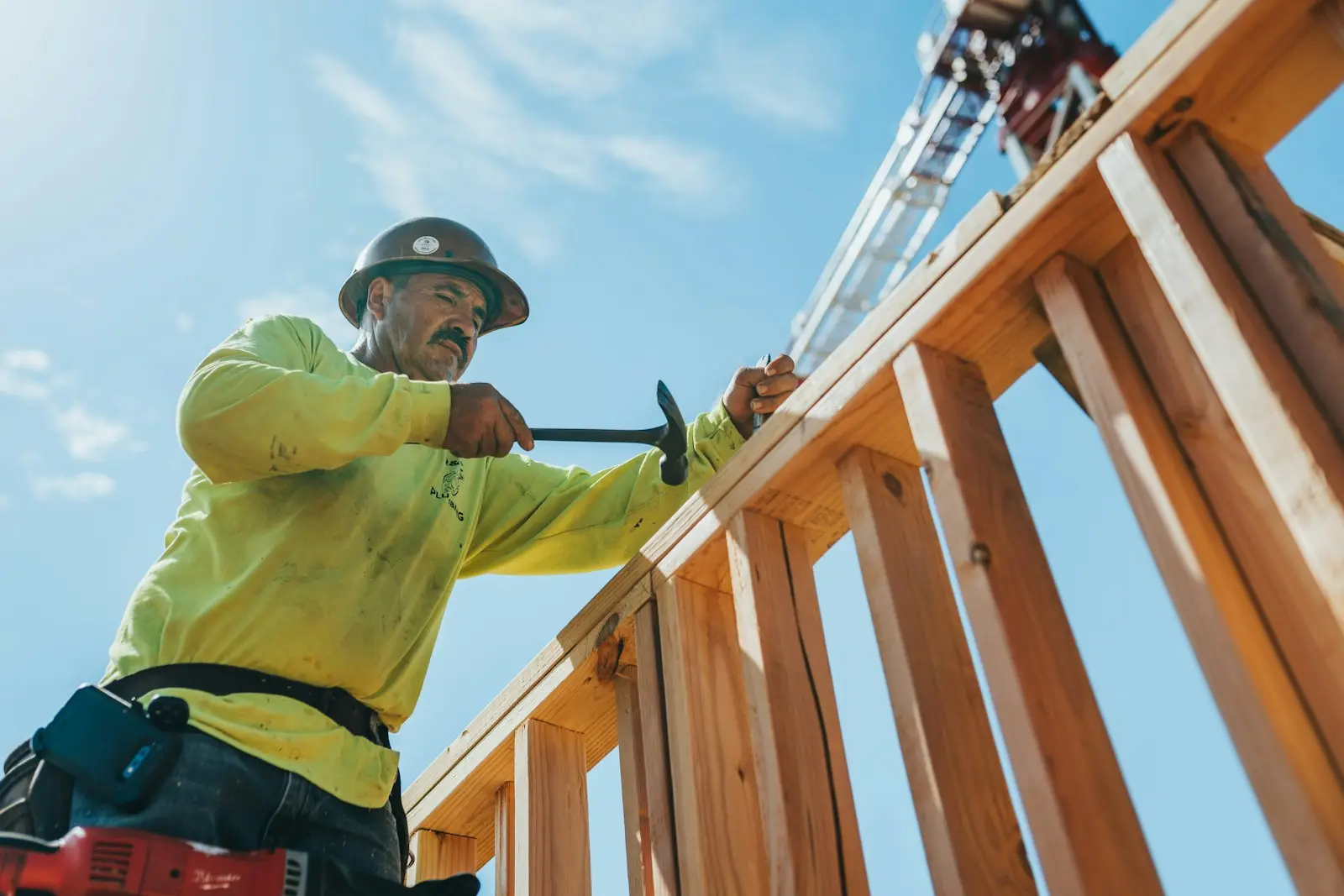 Charpentier fixant une ossature en bois sur un chantier