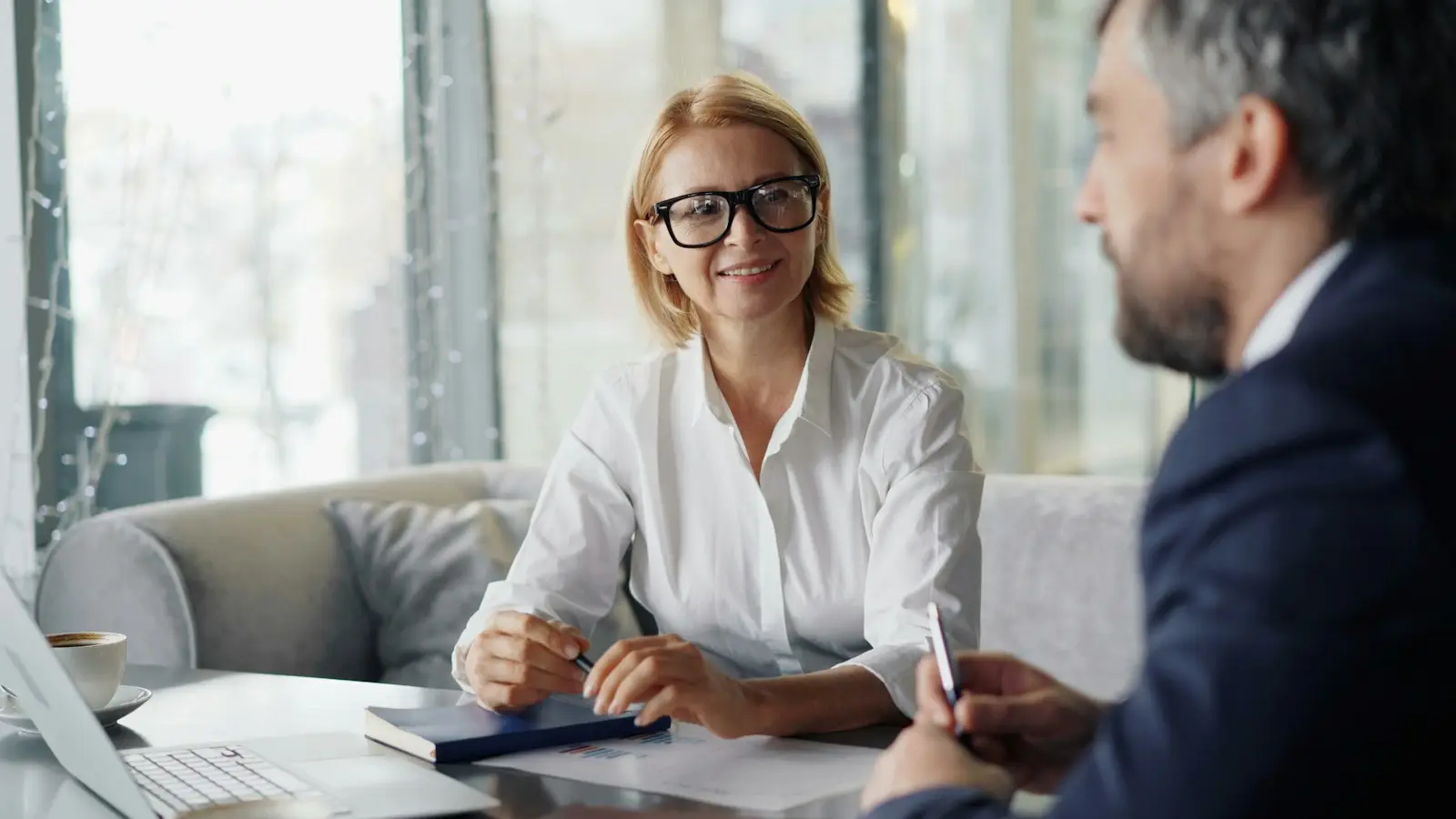 Conseillère souriante prenant des notes face à un client