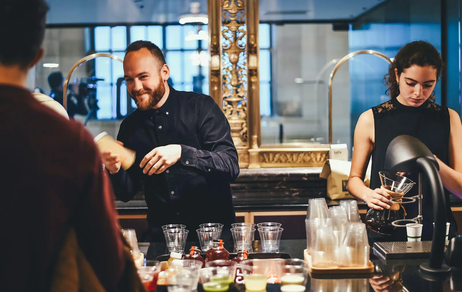 Barman et serveuse préparant des boissons derrière un comptoir