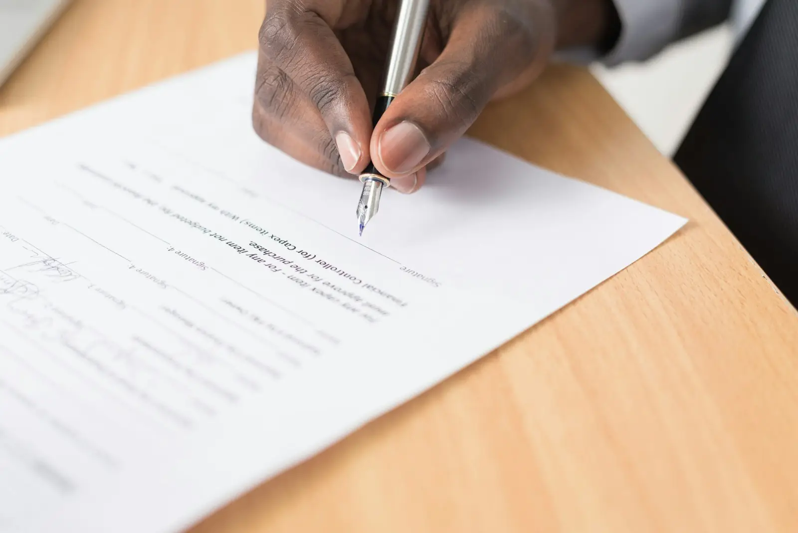 Signature d’un document au stylo sur un bureau en bois
